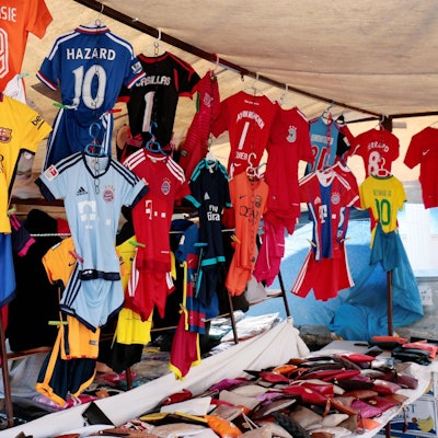 Gefälschte Fußballtrikots hängen an einem Marktstand.