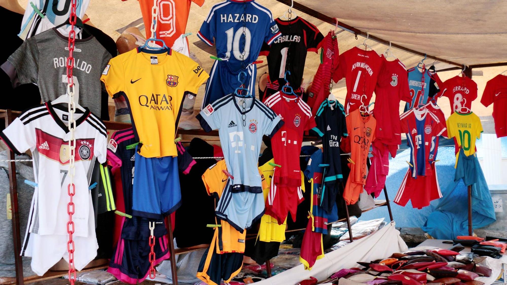 Gefälschte Fußballtrikots hängen an einem Marktstand.