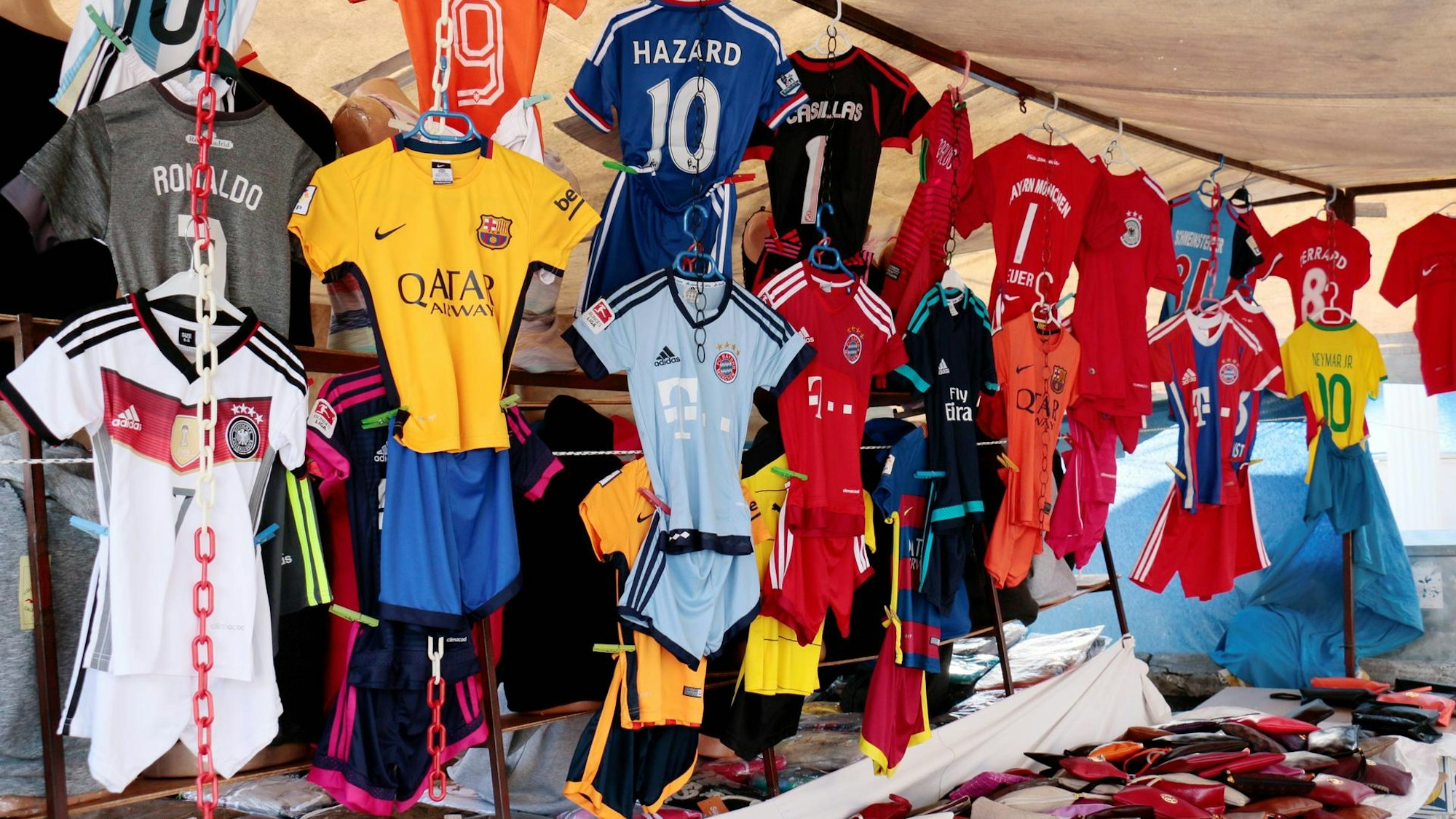 Gefälschte Fußballtrikots hängen an einem Marktstand.