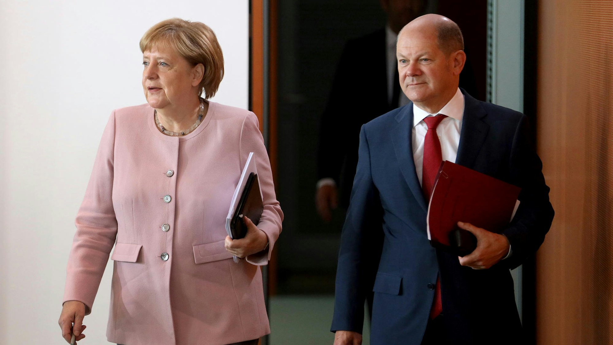 Angela Merkel und Olaf Scholz gehen nebeneinander.