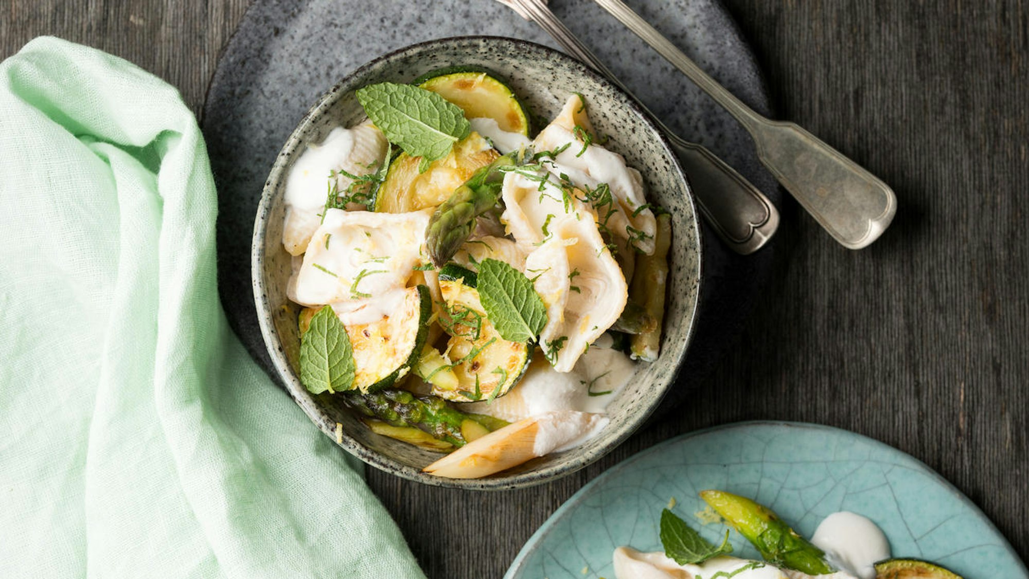 Pasta mit gebratenem Spargel, lecker angerichtet in einem tiefen Teller, verziert mit Minzblättern.
