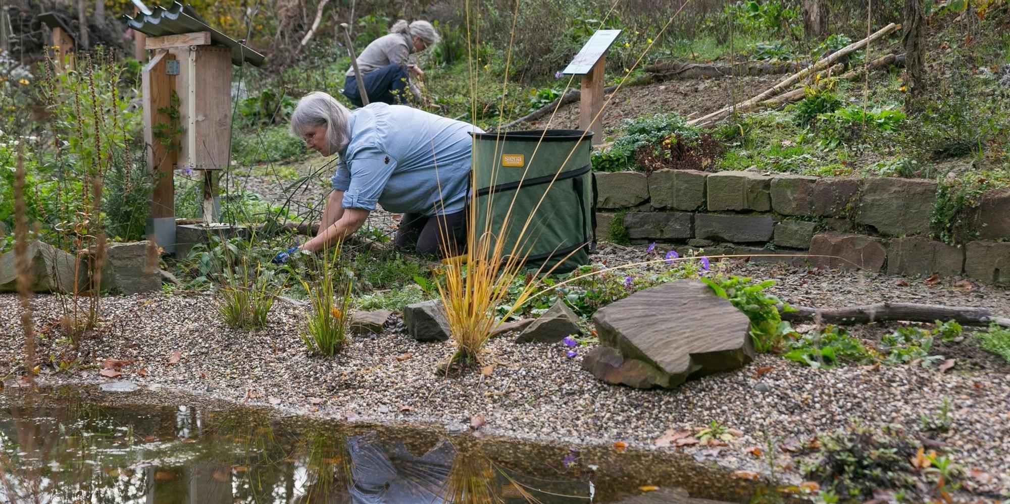 Eine Frau kniet auf dem Boden im Naturschaugarten Reichshof