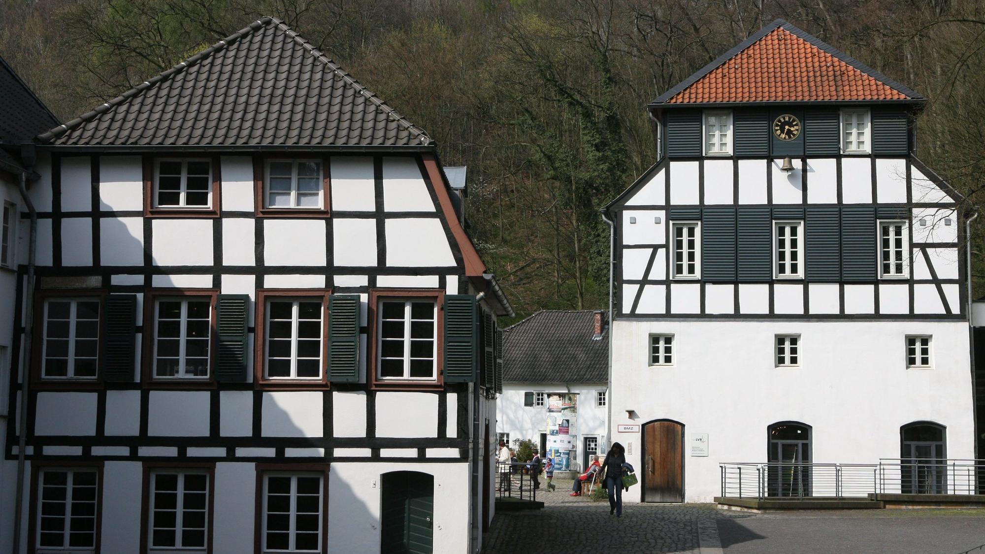 Zwei Fachwerkhäuser mit Wald im Hintergrund.
