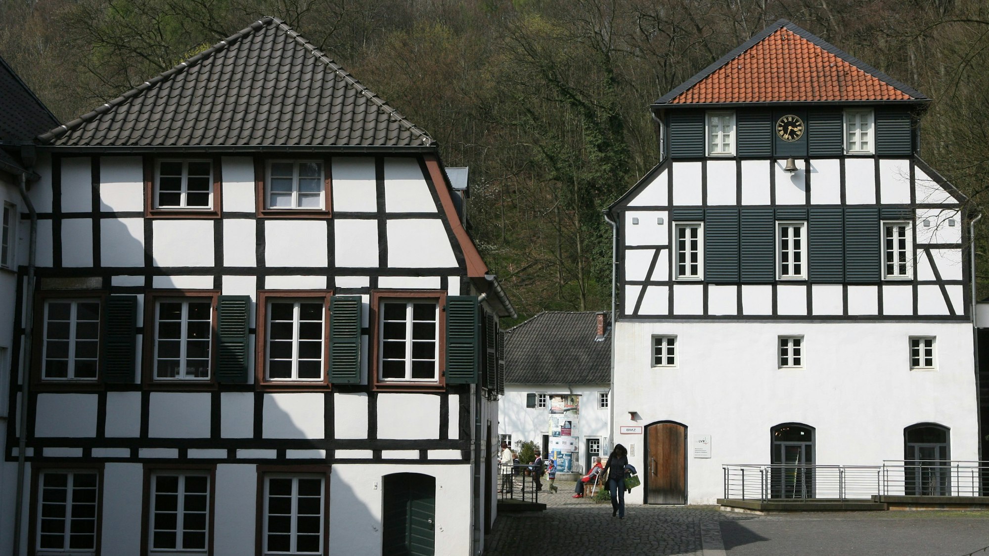 Zwei Fachwerkhäuser mit Wald im Hintergrund.