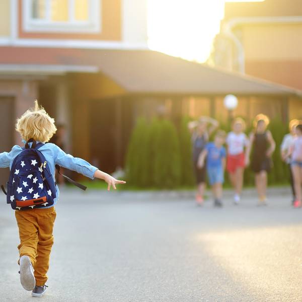 Ein Kind mit Rucksack rennt fröhlich zu anderen Kindern.