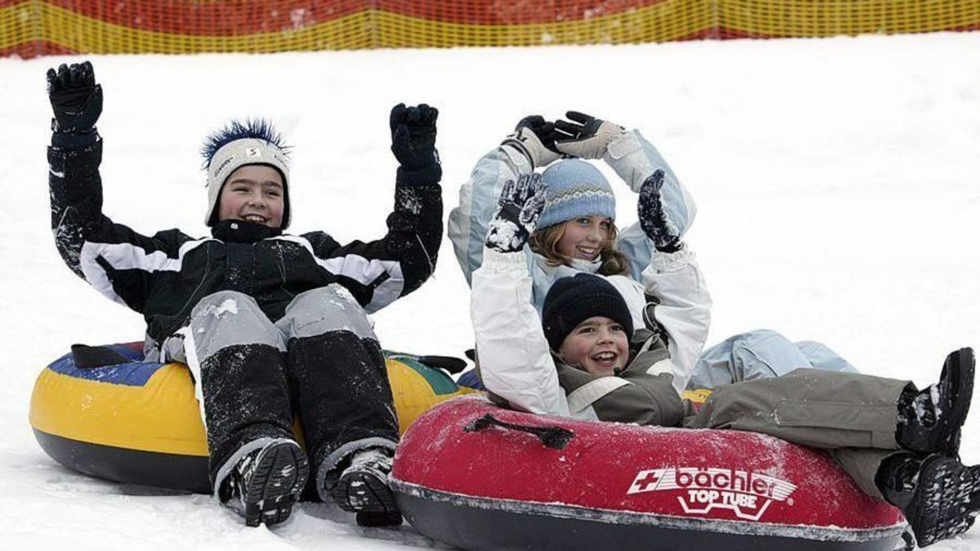 Kinder liegen auf Reifen im Schnee