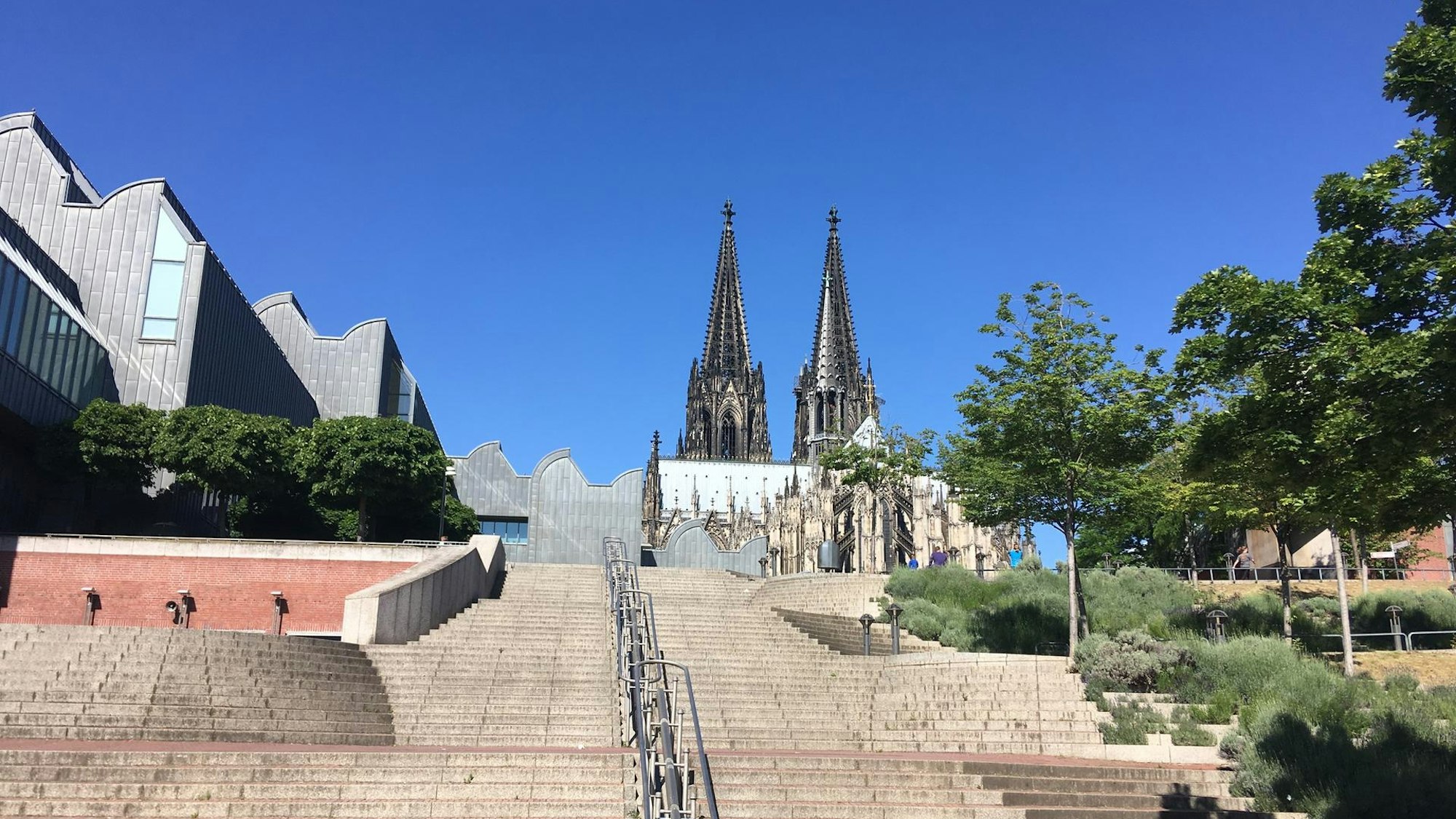 Treppen in Köln am Rhein mit Domspitzen im Hintergrund.