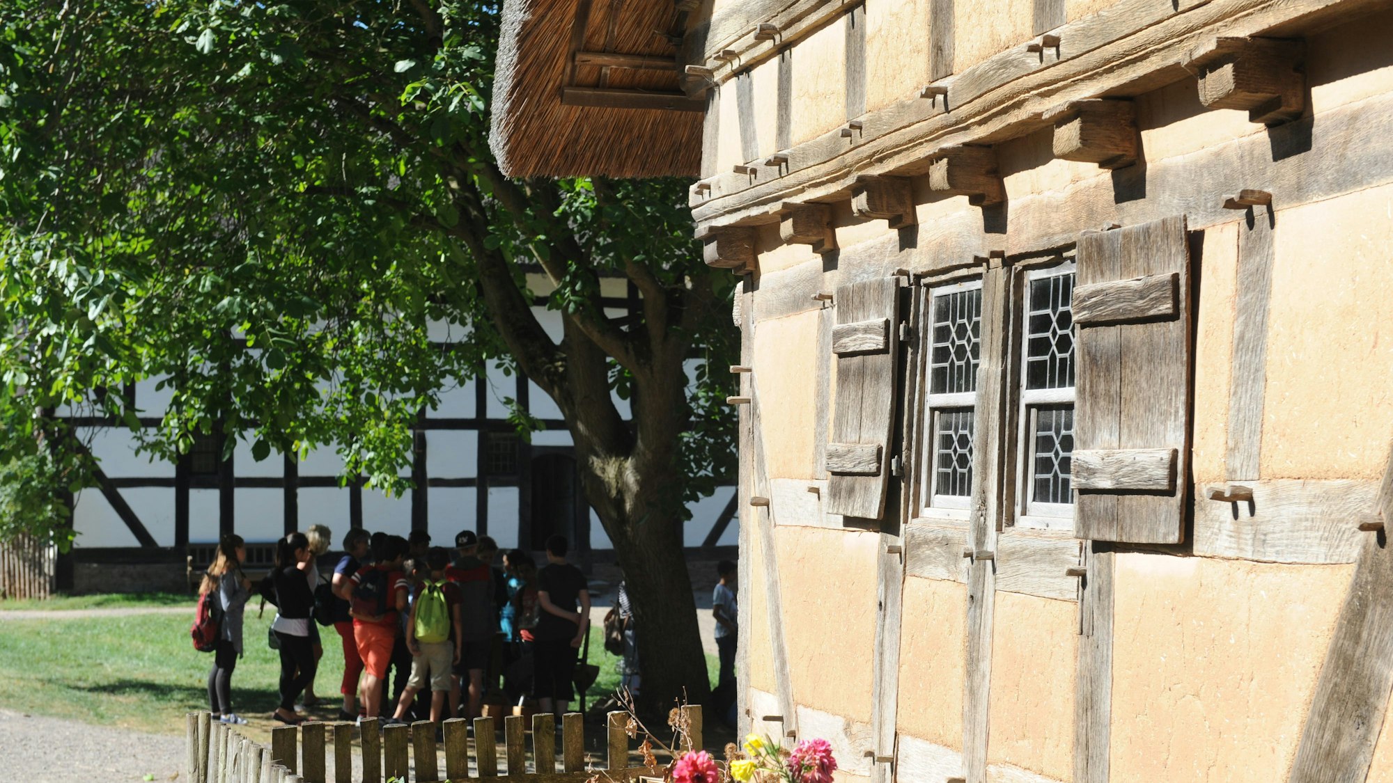 Kinder stehen unter einem Baum zwischen Fachwerkhäusern