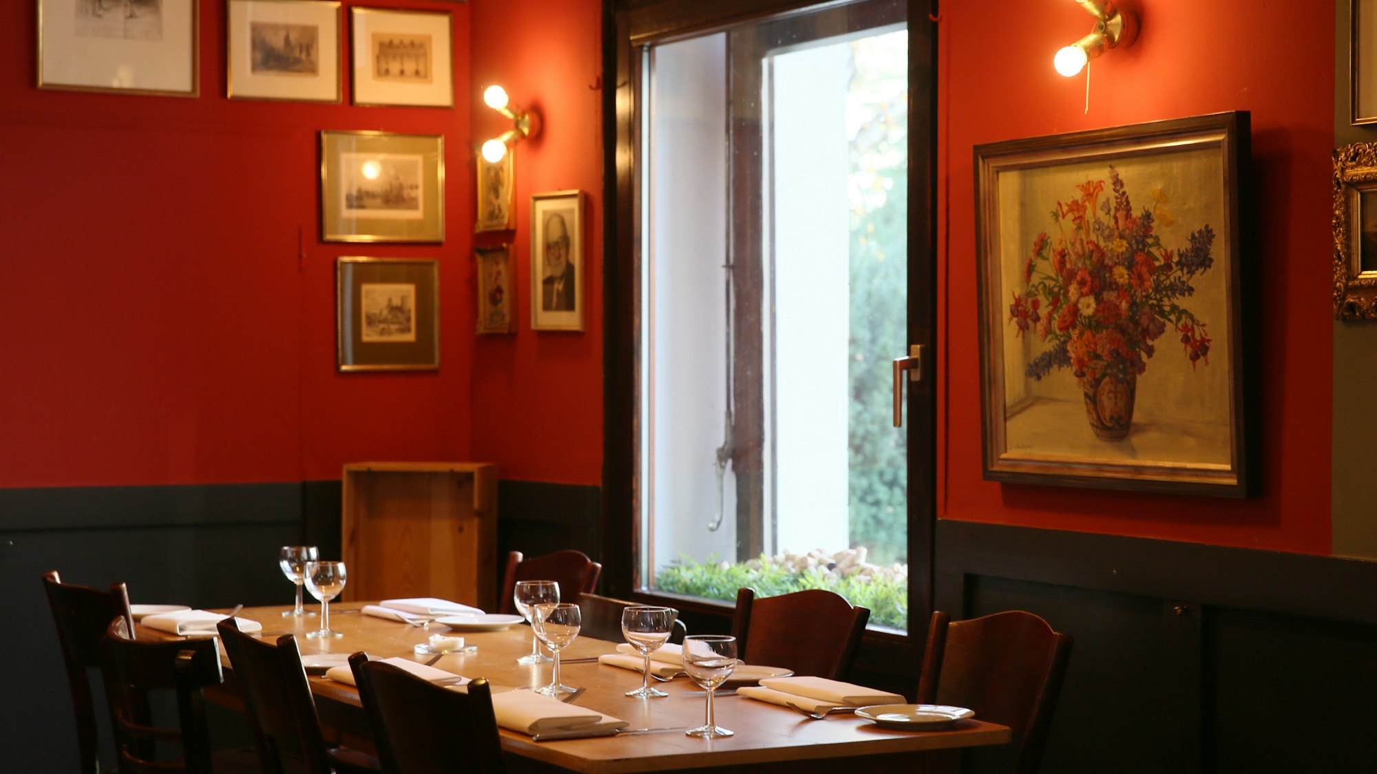 Ein Tisch im Restaurant Brasserie Marie in Köln, dahinter an roten Wänden viele Bilder.