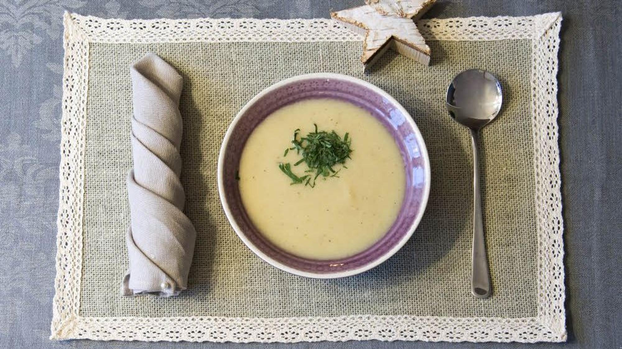 Pastinakensuppe lecker angerichtet in einer Schüssel und serviert auf einem Deckchen mit Besteck und einem Deko-Stern.