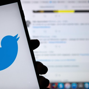 Ein Handy ziegt das Twitter-Logo vor einem Bildschirm, auf dem Twitter geöffnet ist.