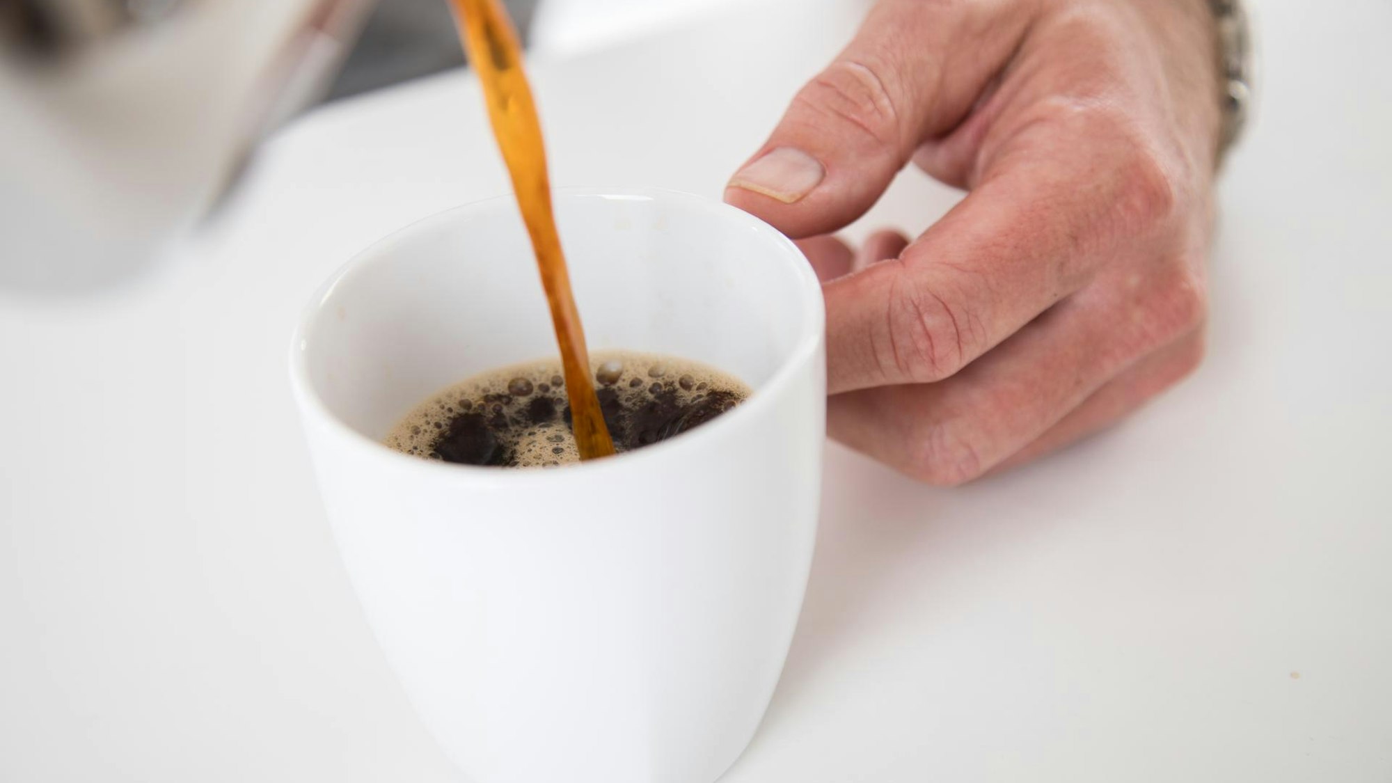 Jemand schüttet sich eine Tasse Kaffee ein