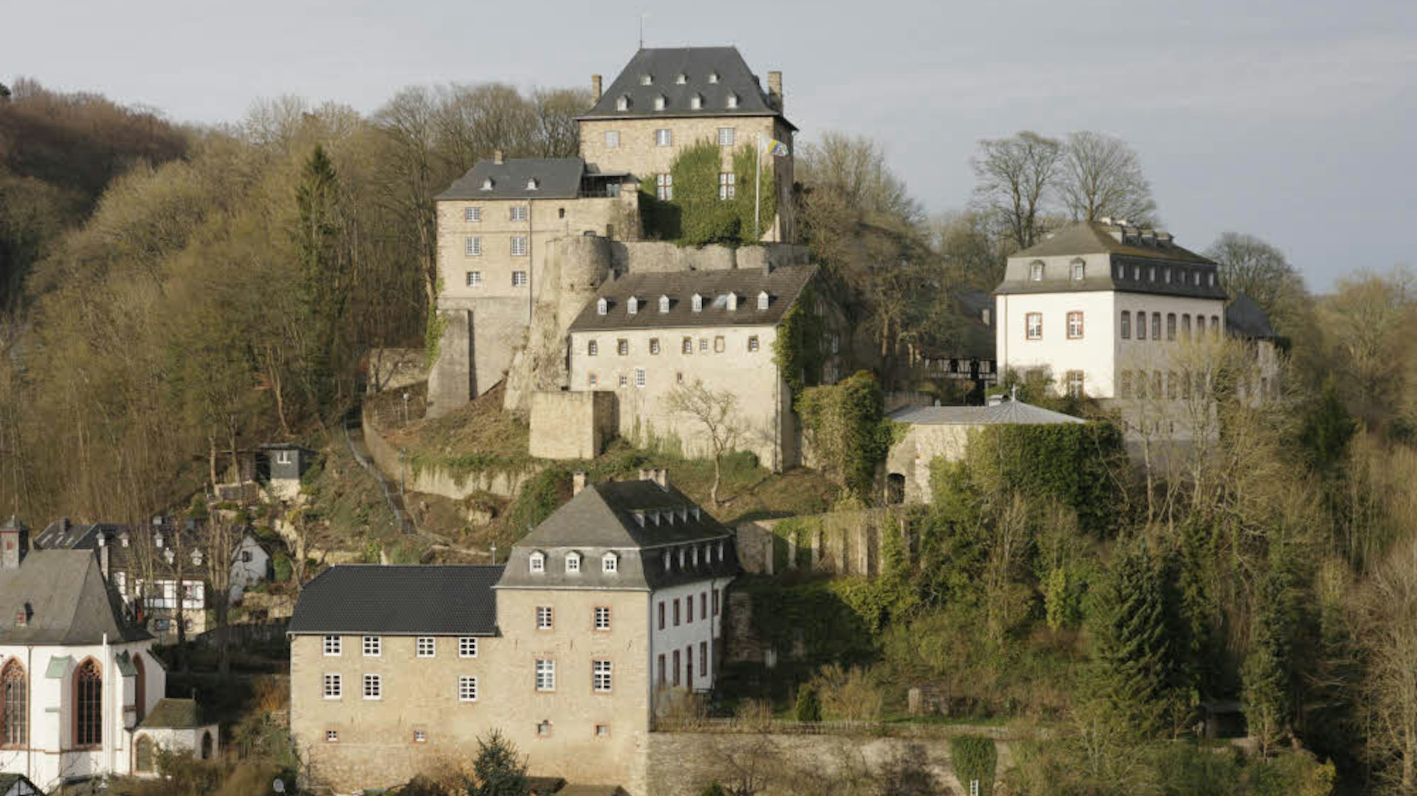mehrere Gebäude auf einem Berg, drumherum Wald