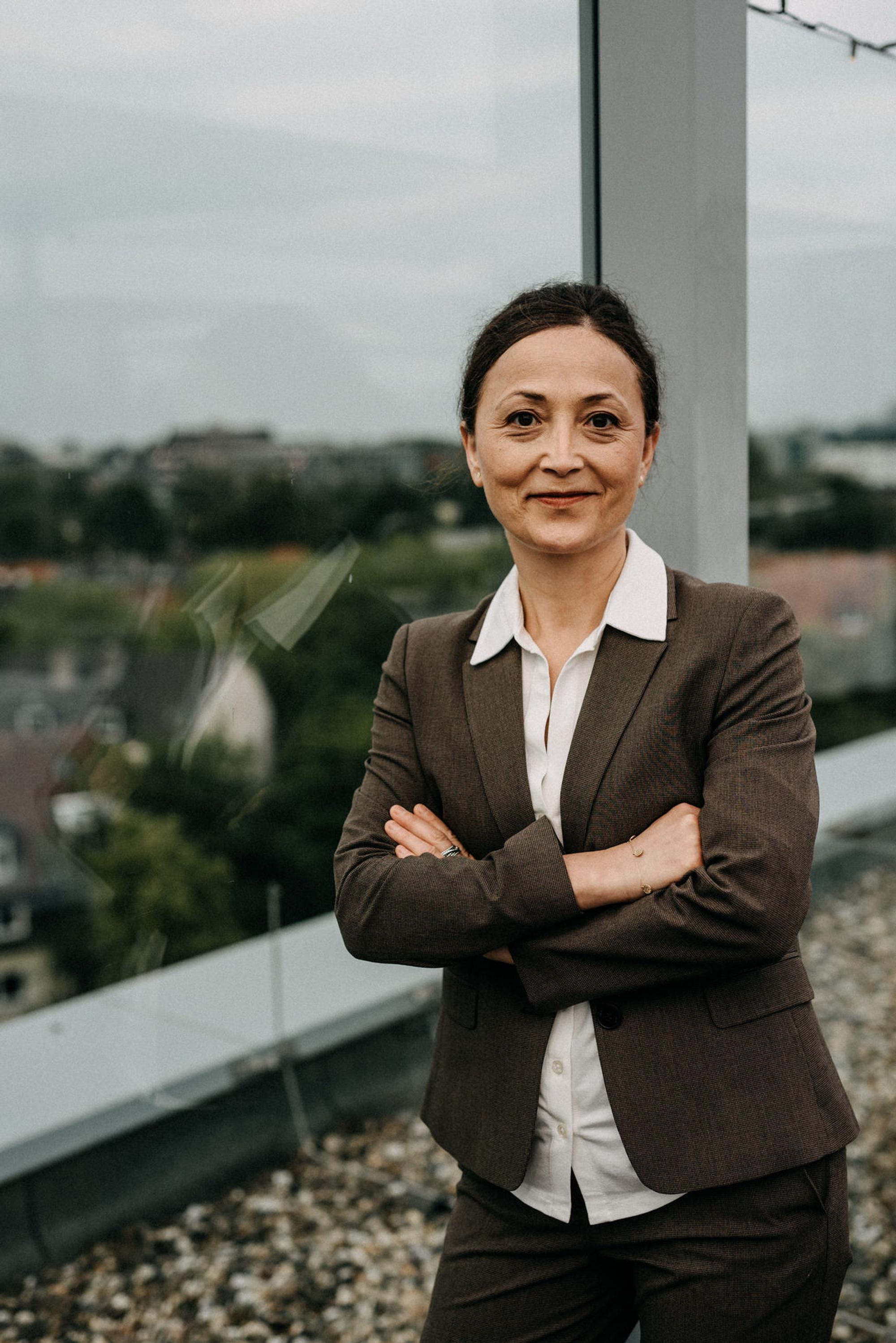 Ayla Celik, Vorsitzende der Gewerkschaft für Erziehung und Wissenschaft (GEW) steht im brauen Anzug vor dem Fenster.