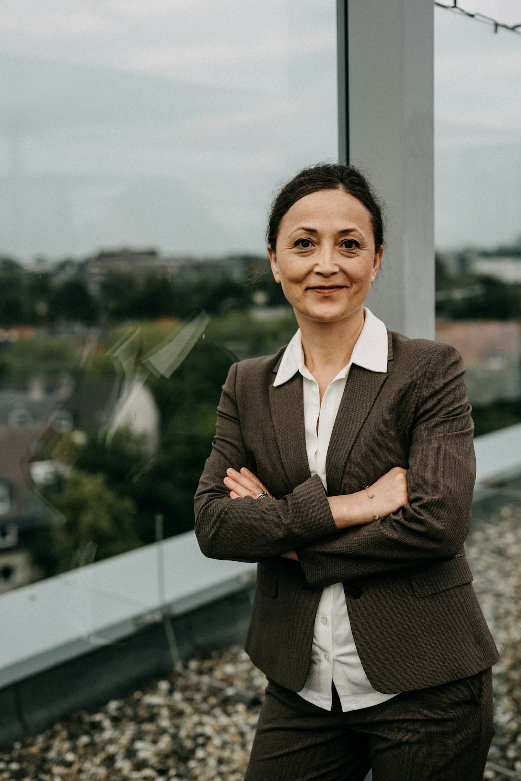 Ayla Celik, Vorsitzende der Gewerkschaft für Erziehung und Wissenschaft (GEW) steht im brauen Anzug vor dem Fenster.
