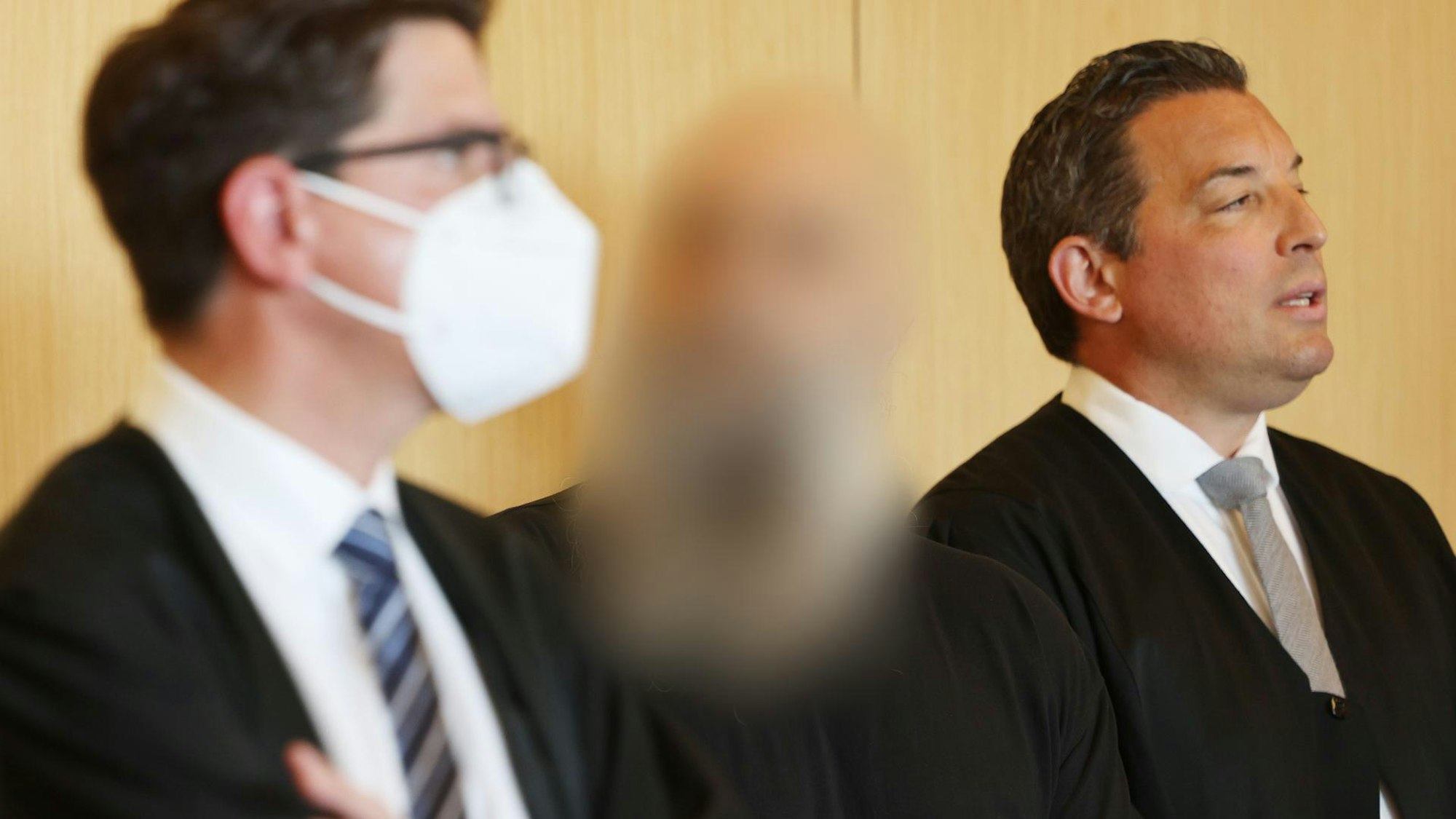 Badia Al-Zein steht am ersten Prozesstag zwischen Anwälten. Sein Gesicht ist verpixelt.