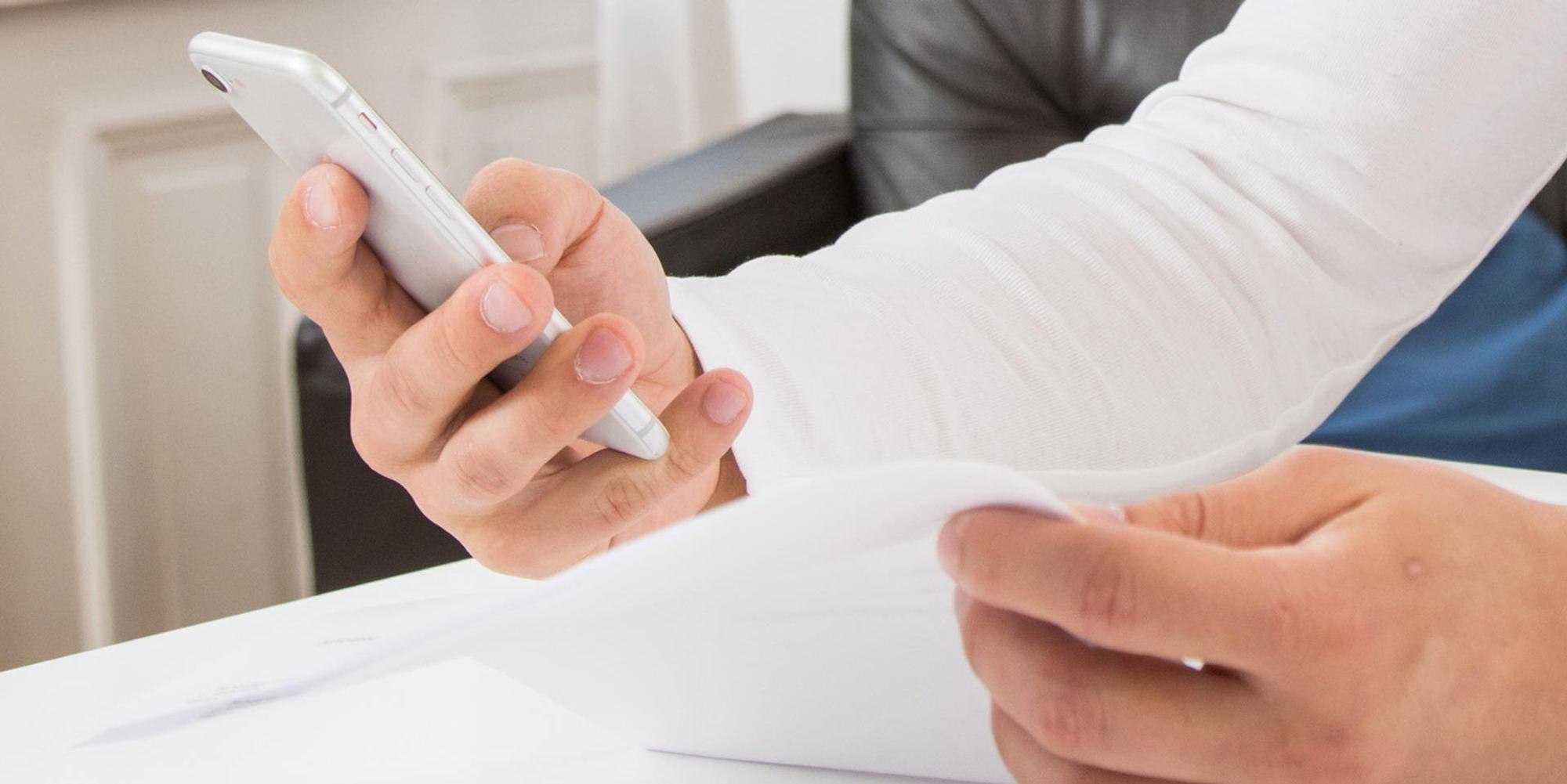 Mann schaut auf sein Smartphone und eine Rechnung