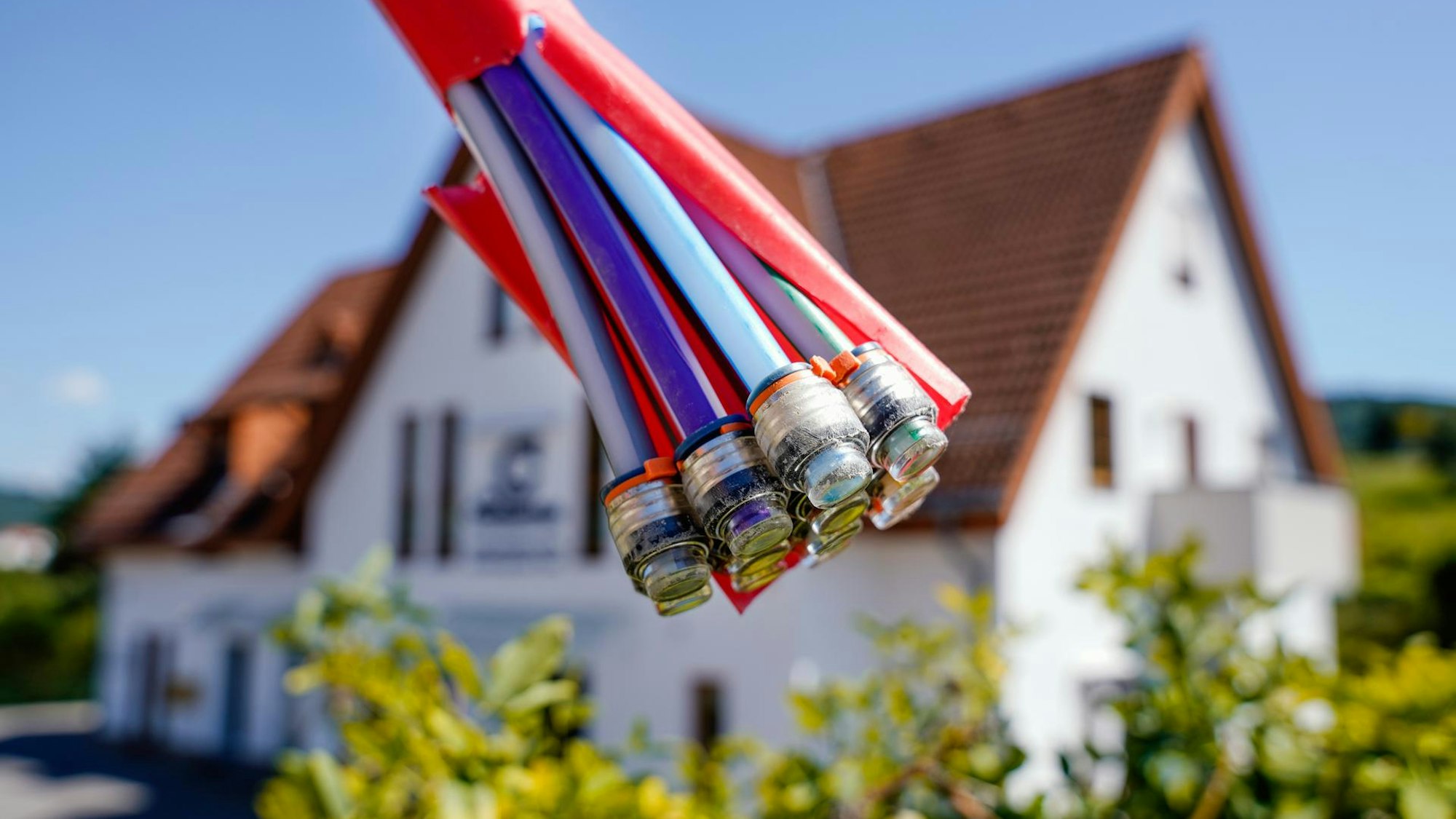 Ein Bündel Glasfaserkabel vor einem Wohnhaus