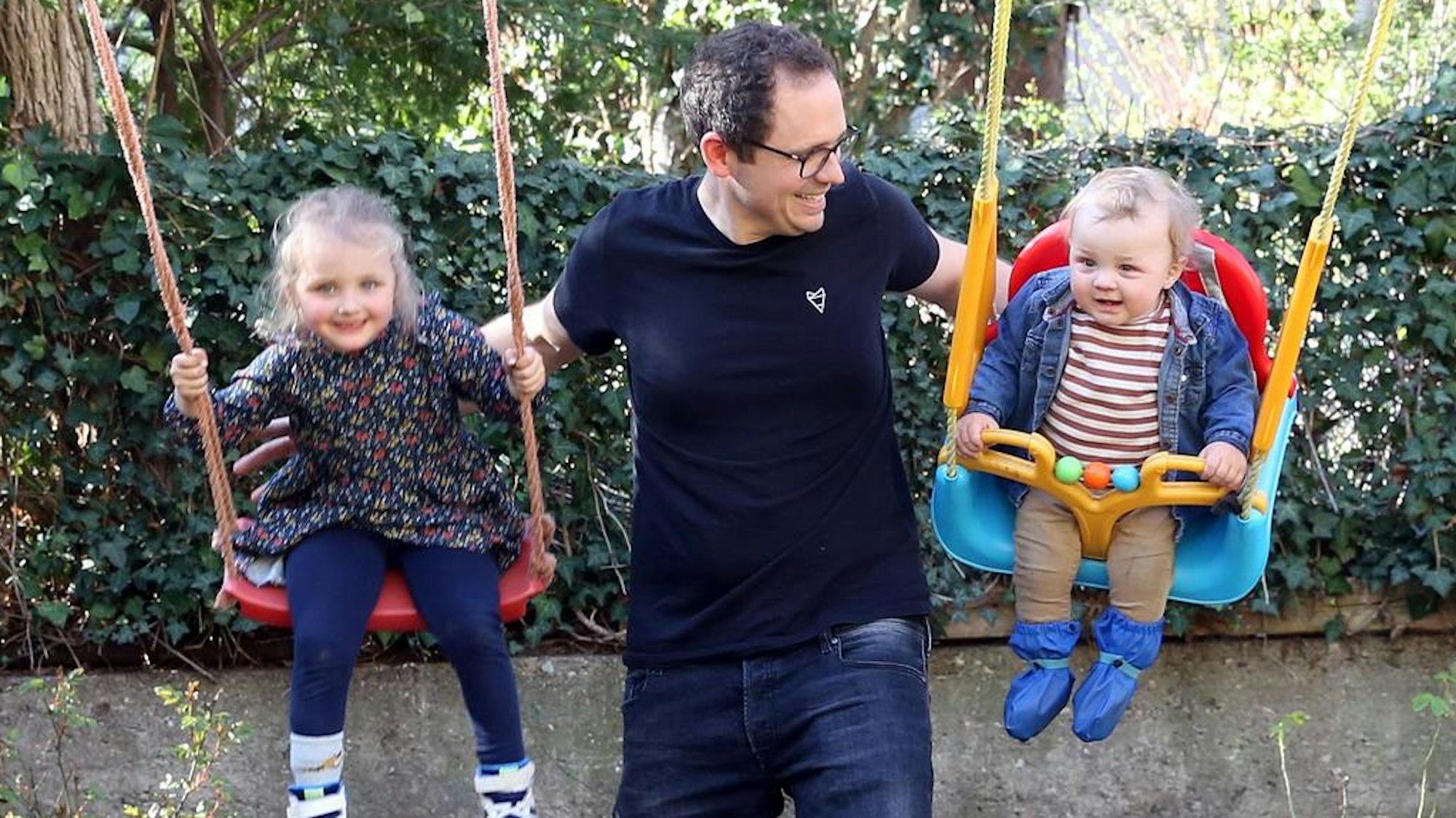 Simon Hölzemann schubst seine Kinder auf der Schaukel an.