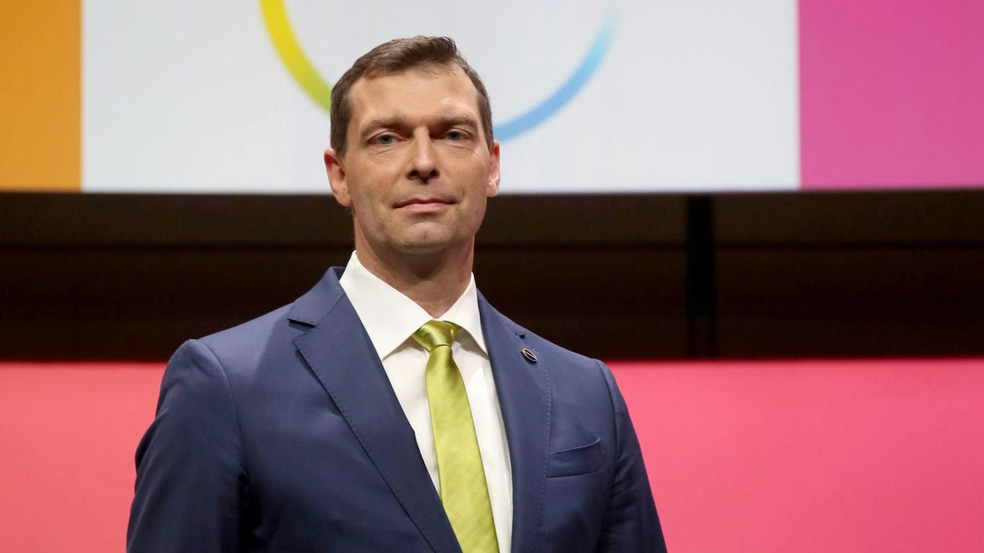 Covestro-Chef Markus Steilemann steht im Anzug vor einer bunten Wand.