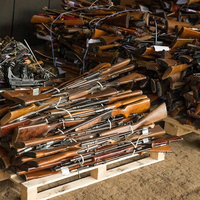 Gewehre liegen als Stapel auf einer Palette.