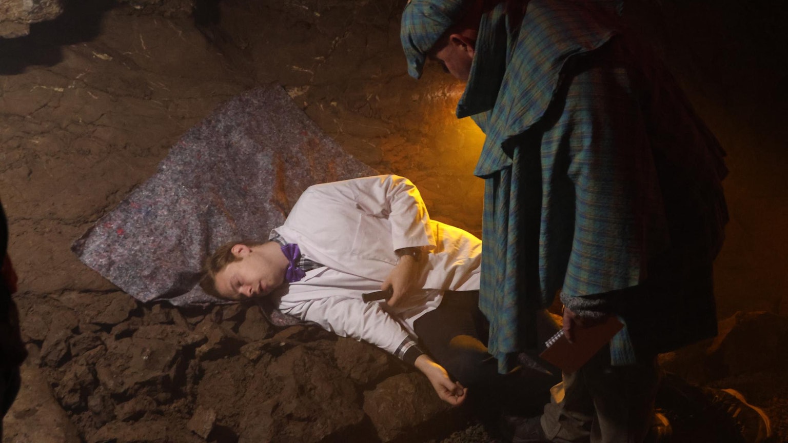 Ein Mann liegt auf dem Boden, ein anderer schaut ihn an.