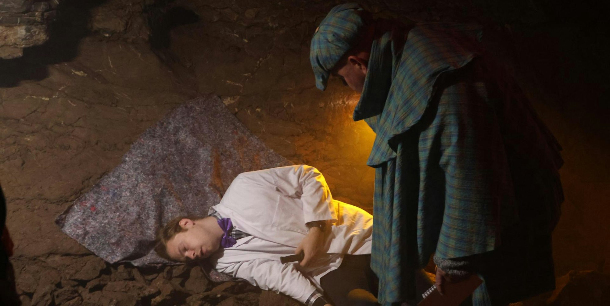 Ein Mann liegt auf dem Boden, ein anderer schaut ihn an.