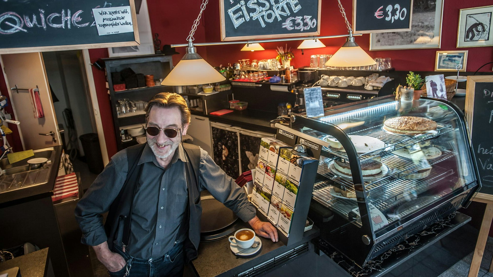 Ein Mann steht an einer Theke, neben ihm steht ein Cappuccino.