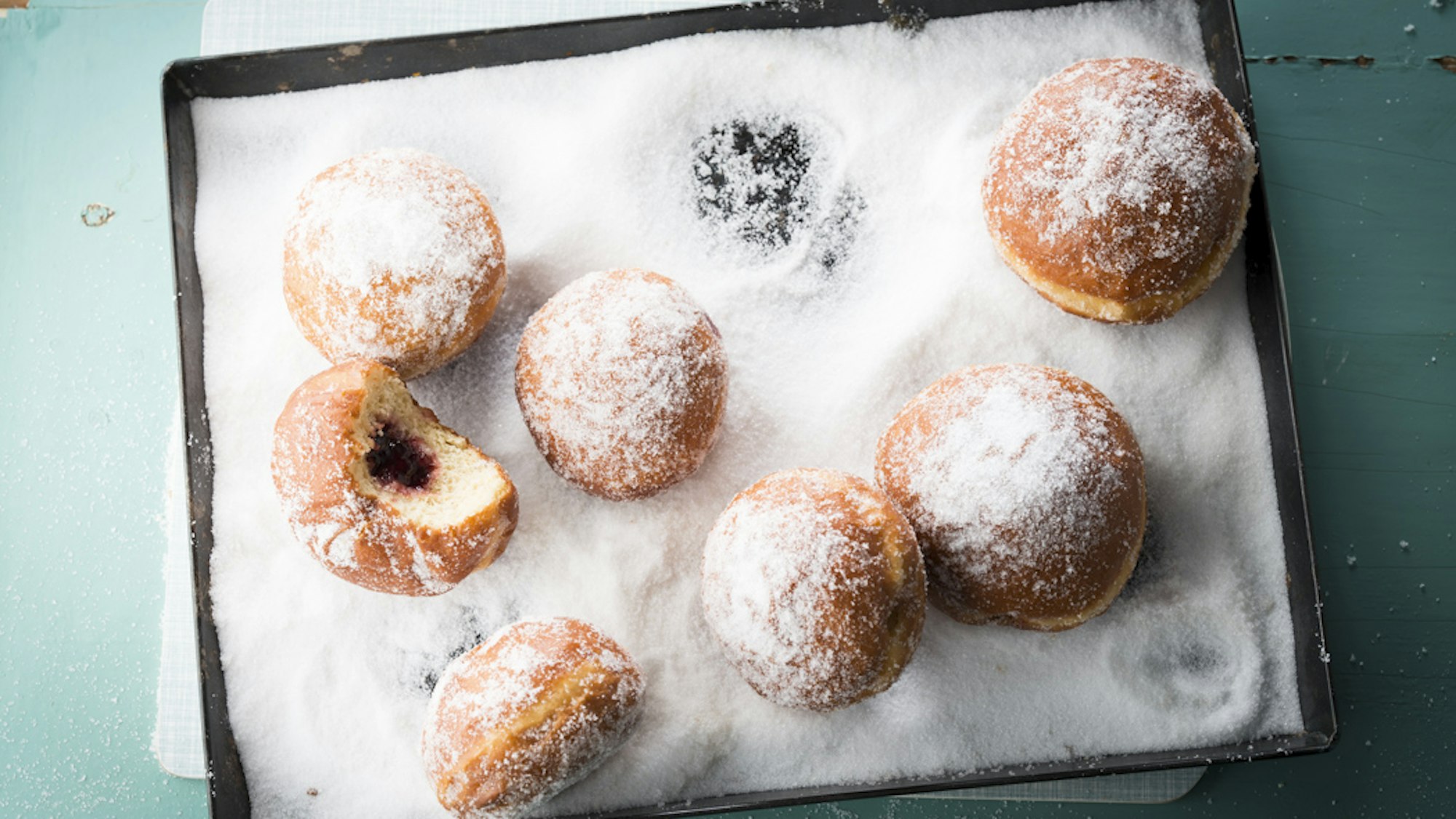 Berliner liegen im Puderzucker auf einem Backblech