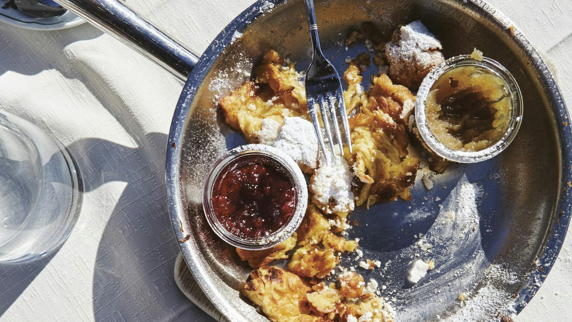 Kaiserschmarrn mit Marmeladen und Puderzucker auf einem Teller angerichtet.