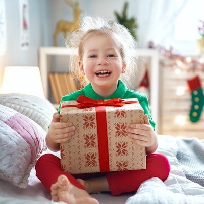 Ein Mädchen hält lachend ein Geschenk in den Händen.