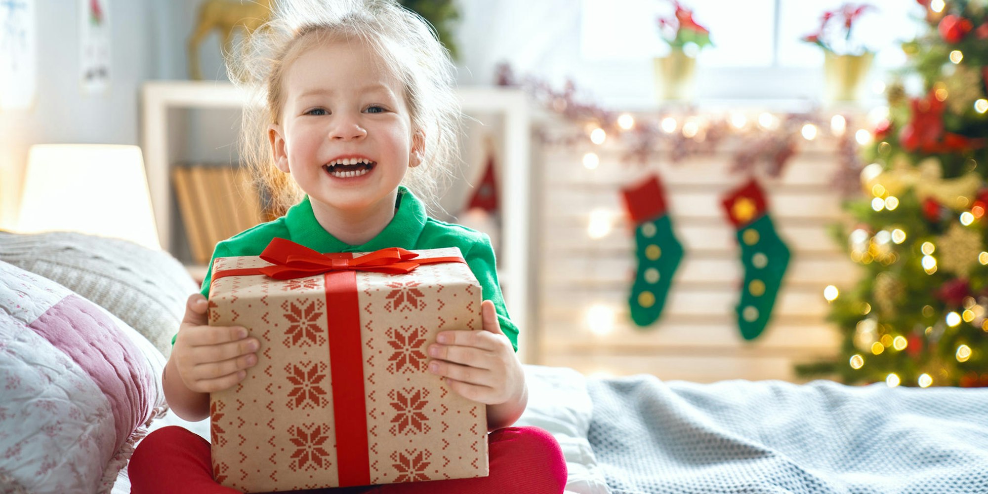 Ein Mädchen hält lachend ein Geschenk in den Händen.