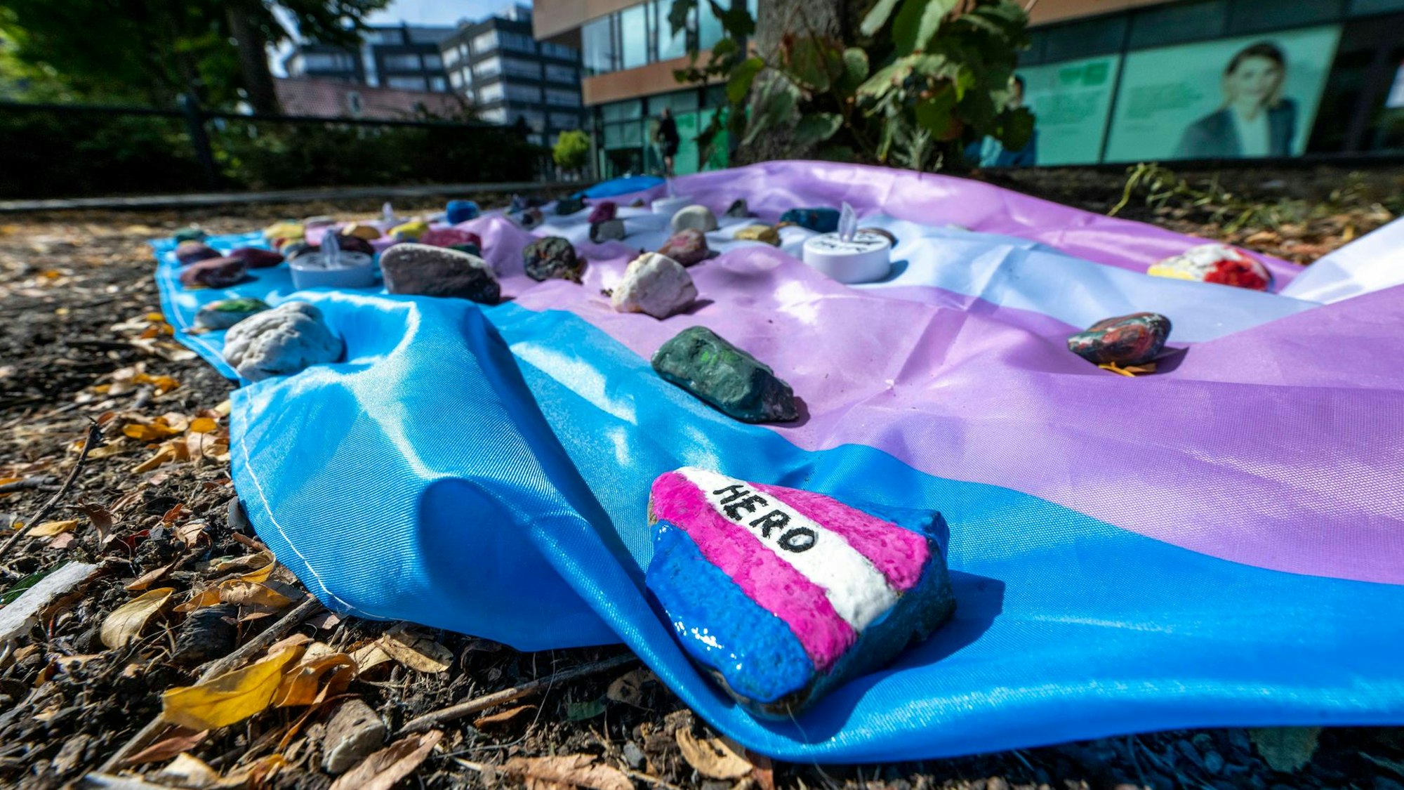 Eine Fahne liegt als Andenken an Malte C., beschwert von Steinen, auf den „Hero“ steht, auf dem Boden.