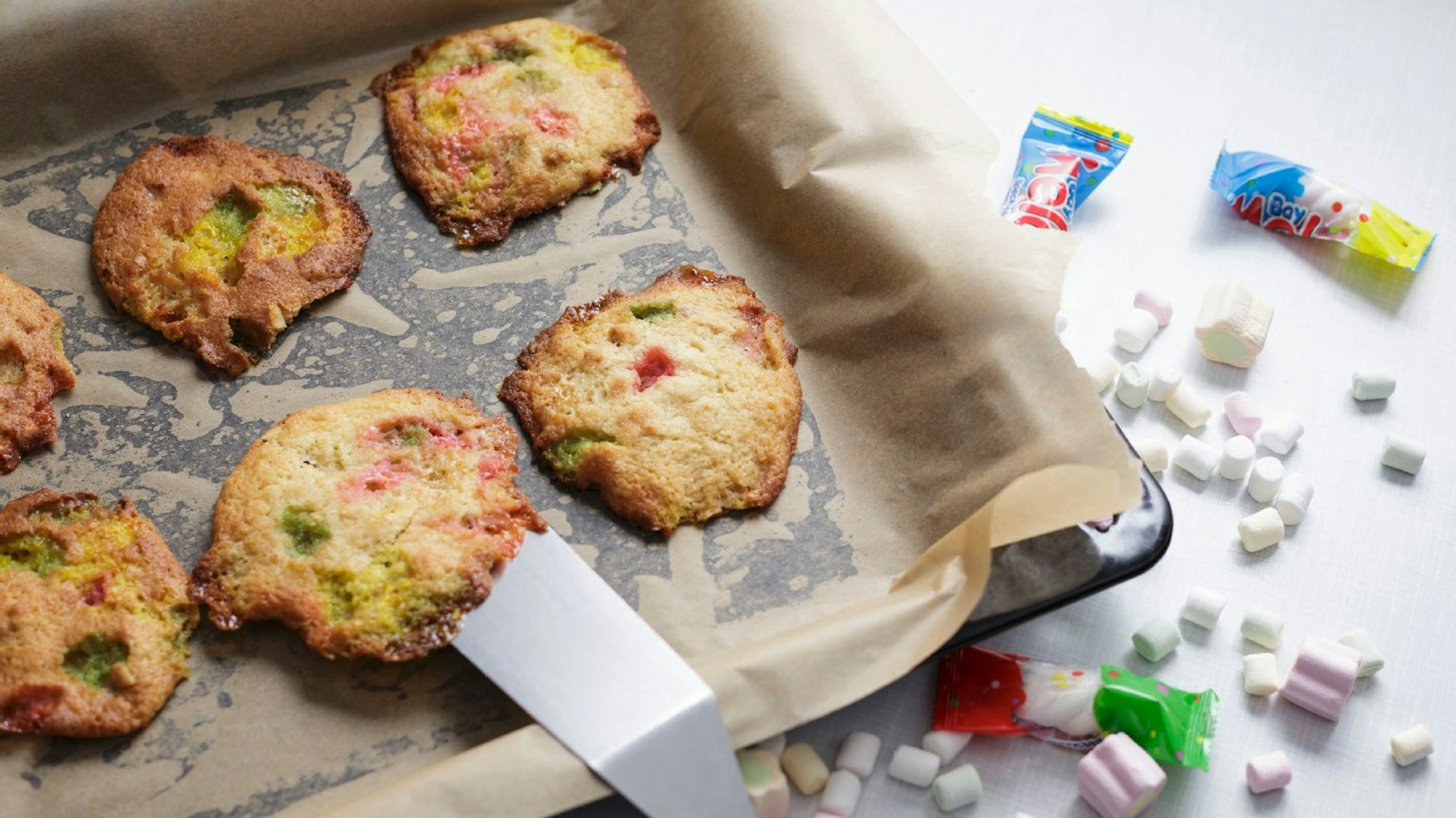 Kekse auf einem Backblech, daneben kleine Marshmallows