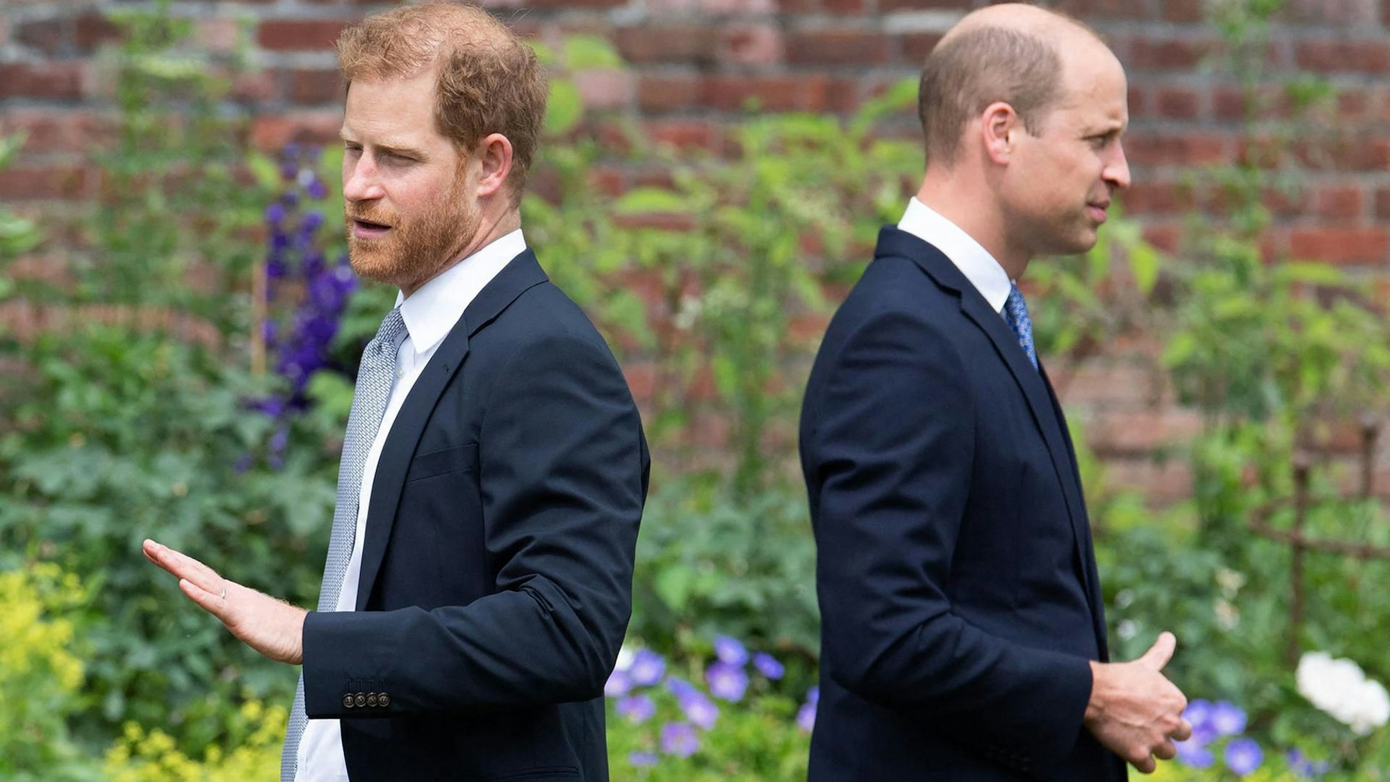 Prinz Harry und Prinz William stehen mit dem Rücken zueinander.