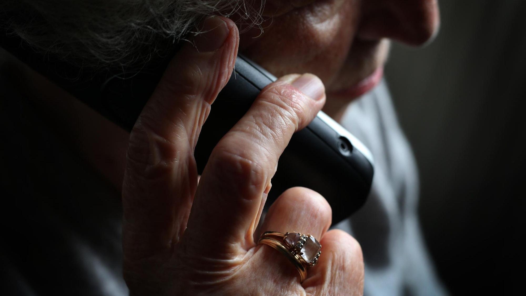 Ältere Frau mit Telefon in der Hand.