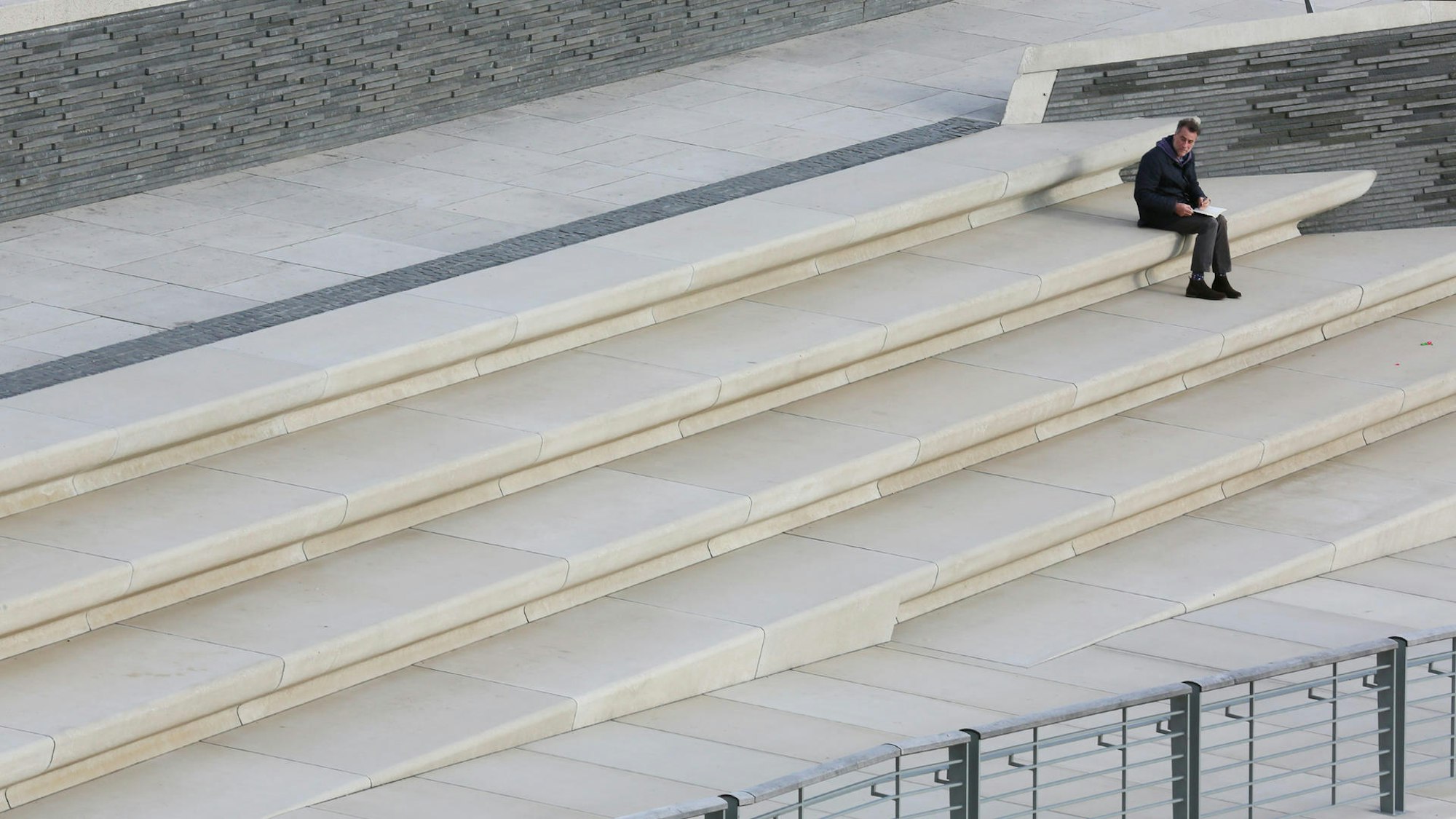 ein Mann sitzt auf den breiten Stufen am Rheinboulevard