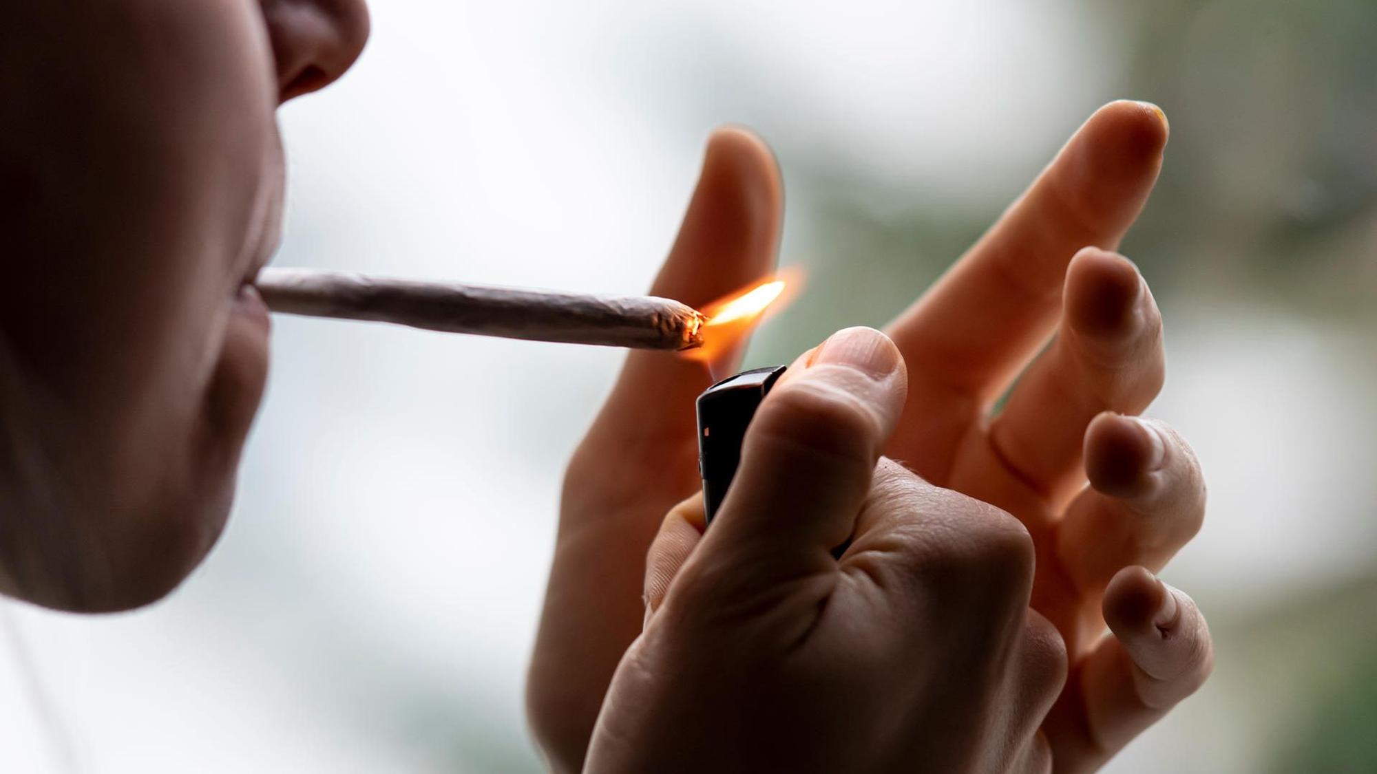 Eine Person zündet sich einen Joint an.
