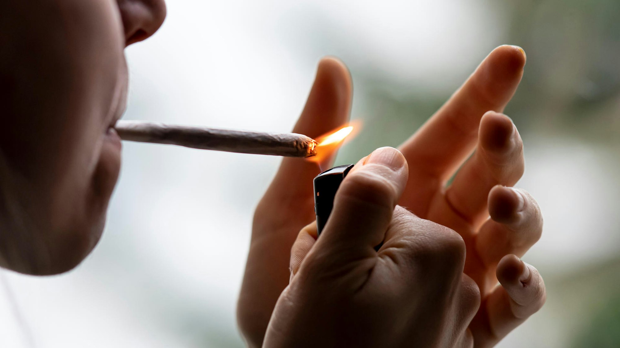 Eine Person zündet sich einen Joint an.