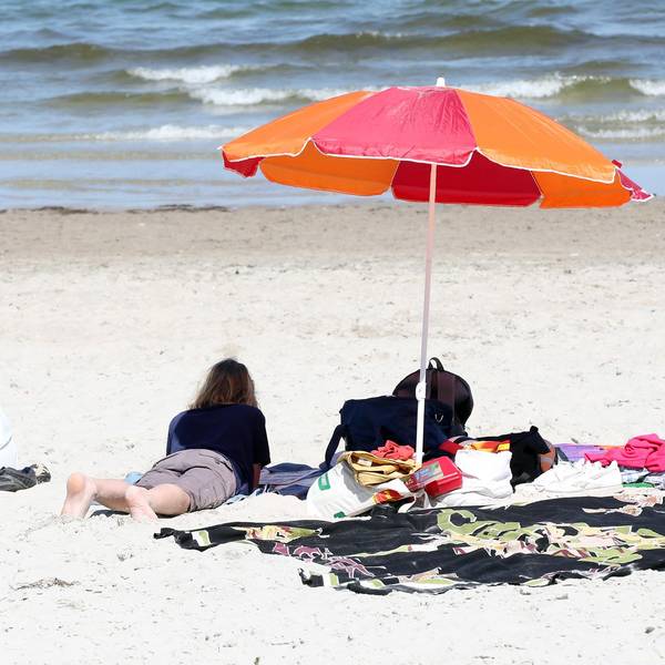 Frau liegt am Strand unter Sonnenschirm