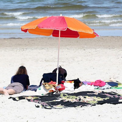 Frau liegt am Strand unter Sonnenschirm