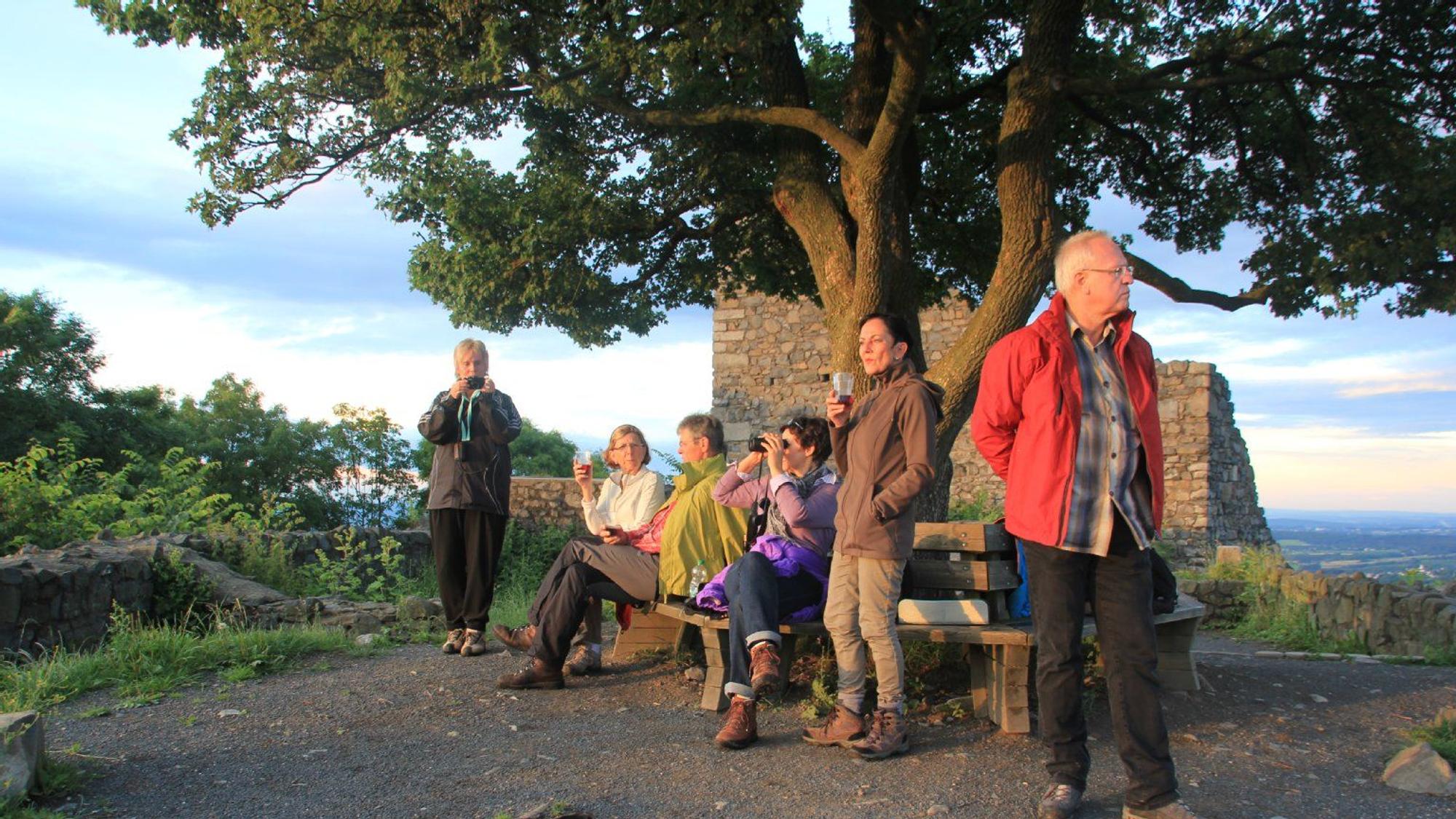Eine Gruppe Wanderer genießt den Sonnenuntergang auf der Löwenburg.