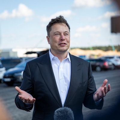 Elon Musk gibt ein Interview auf einem Parkplatz.E