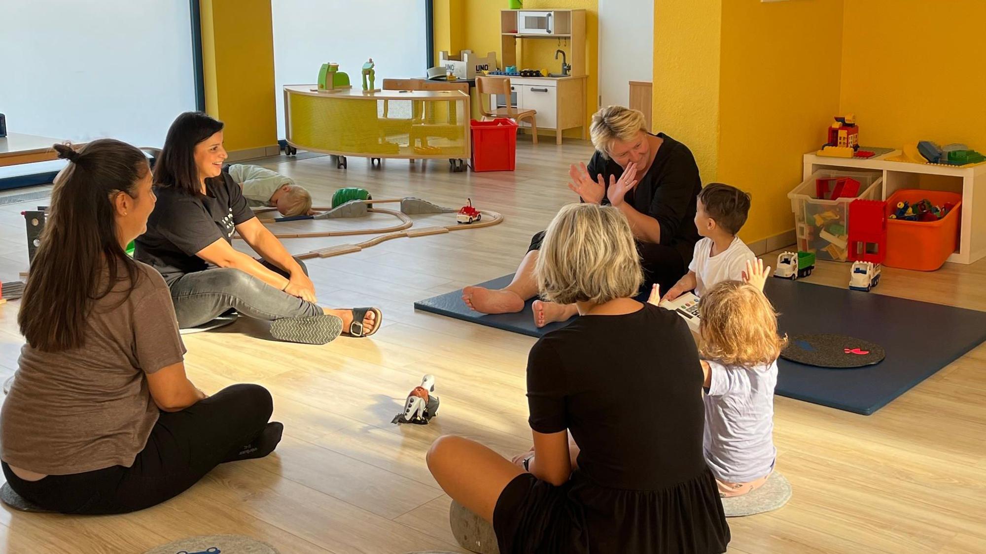 Erwachsene und Kinder sitzen im Kreis und singen