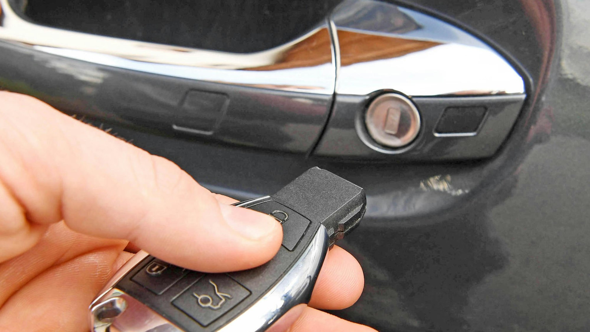 Das Bild zeigt einen Autoschlüssel, der an eine Wagentüre gehalten wird.