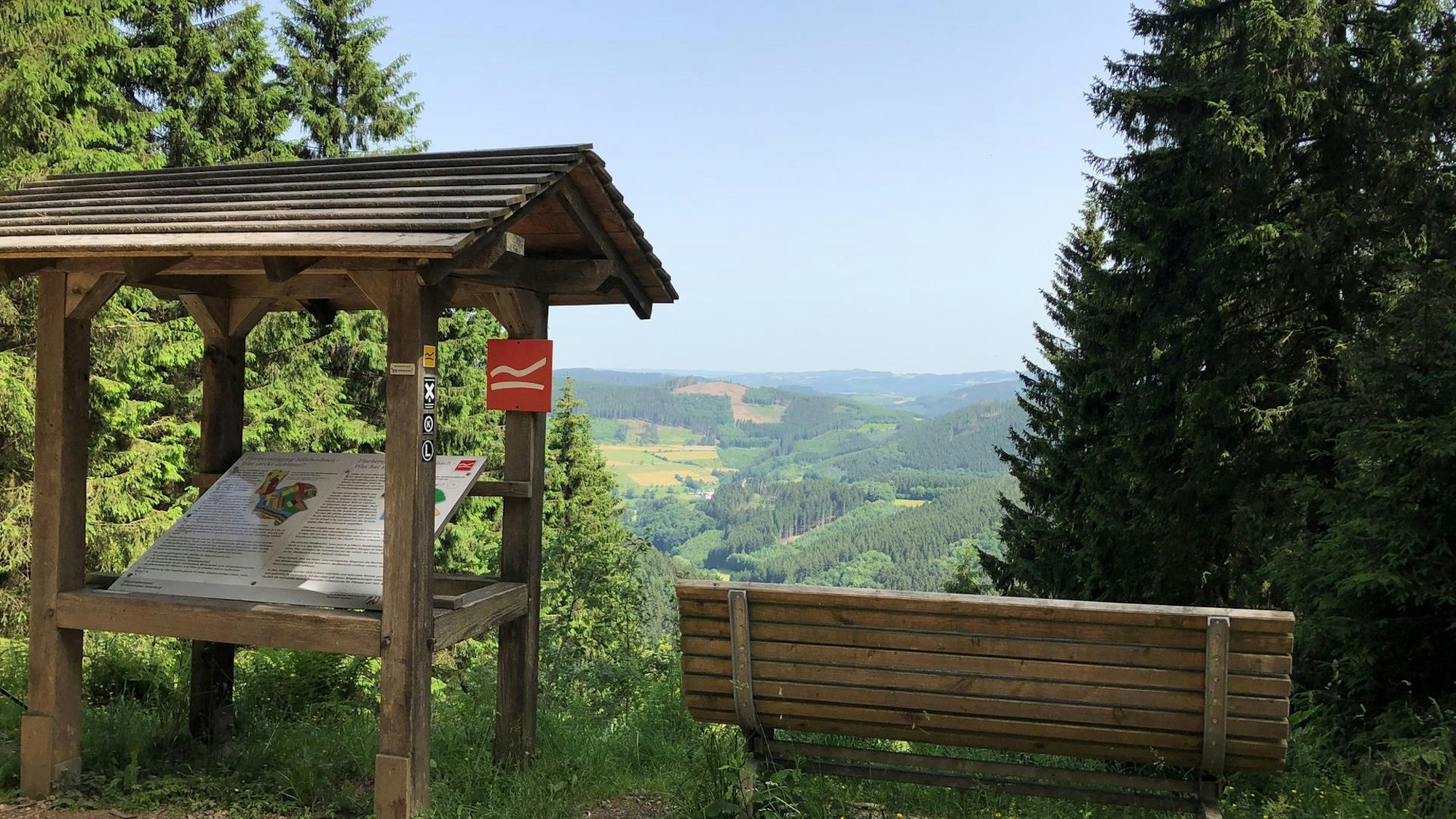 Eine Bank und eine Infotafel an einem Aussichtspunkt im Sauerland