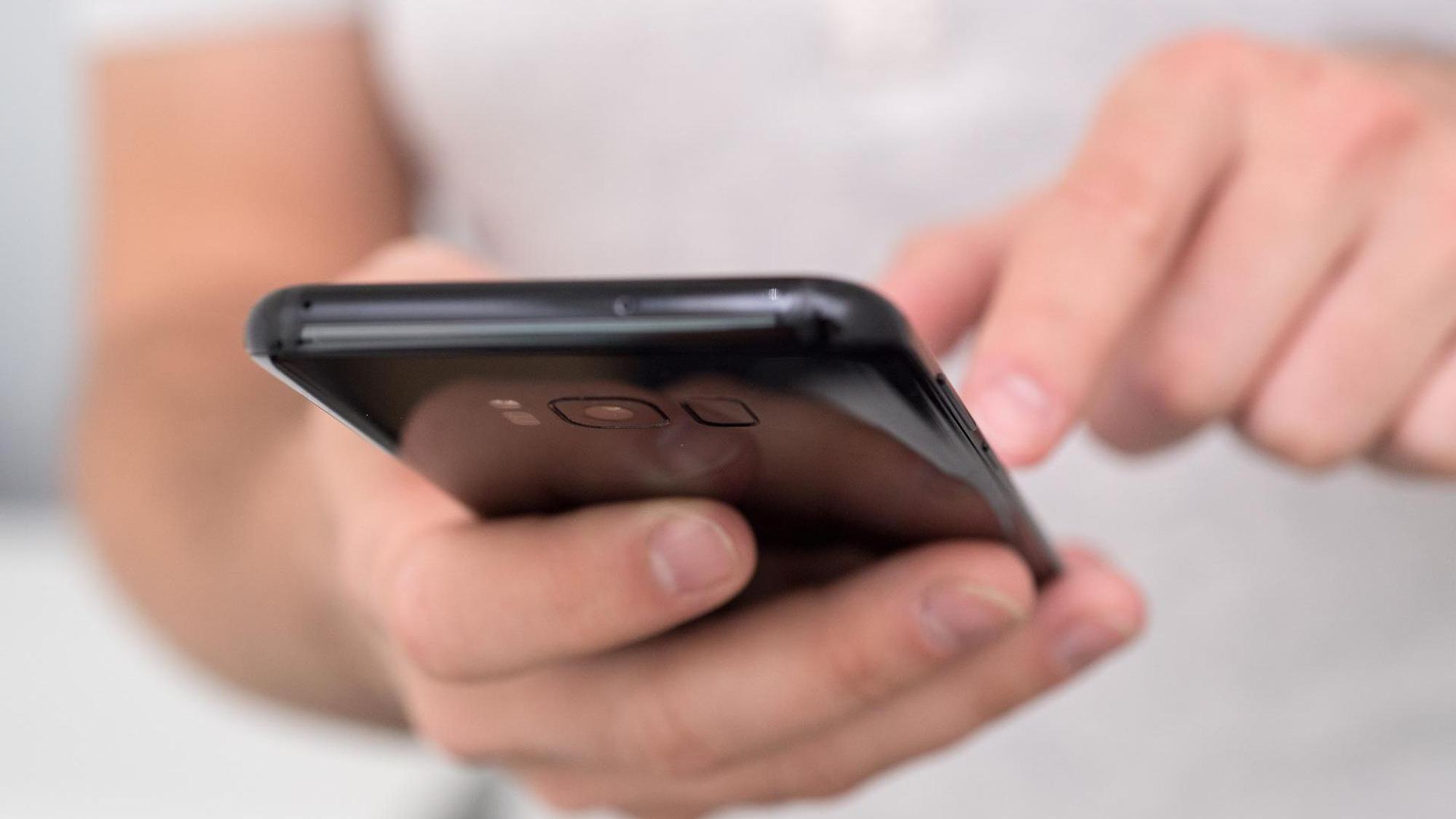 Eine Person klickt auf ihrem Smartphone rum.