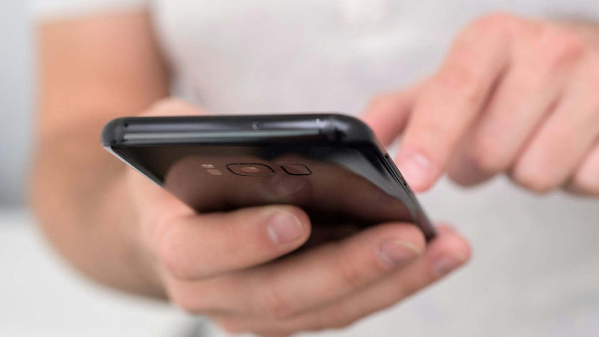 Eine Person klickt auf ihrem Smartphone rum.