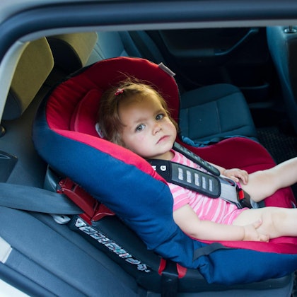 Kleinkind sitzt in einem Autokindersitz.