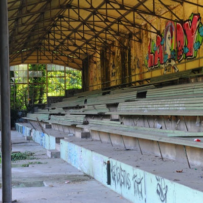 Graffiti an den Wänden und kaputte Bänke zieren die alte Tribüne.